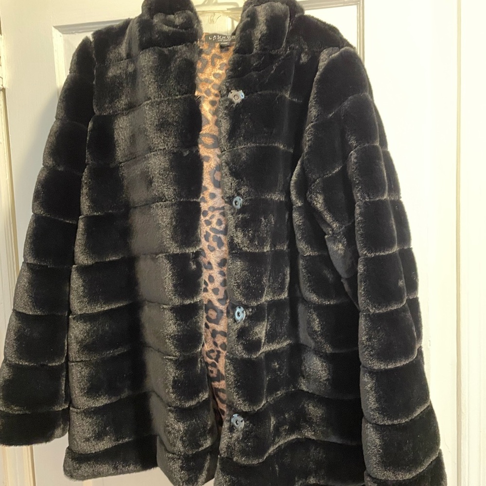 Black faux fur jacket hits below waist .
